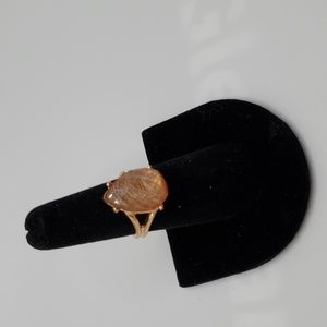 Peach colored ring in gold setting.